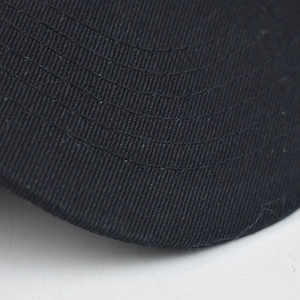 Macro shot of black twill fabric on a baseball cap brim with durable reinforced stitching