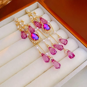 Macro shot of pink crystal teardrop earrings with pearls in a soft velvet jewelry box