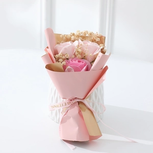 Close-up of pink soap rose bouquet with dried baby's breath in a white textured vase