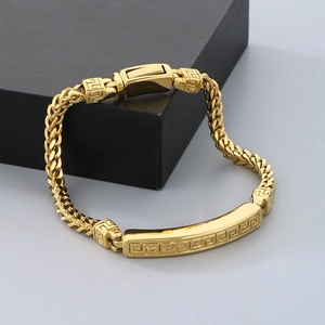 Close-up of golden vintage cloud pattern plaque on a braided wheat chain bracelet