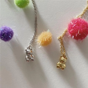 Macro detail of 925 silver bear pendant necklaces in gold and silver with soft pom-poms