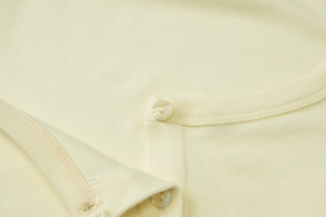 Close-up of knit fabric texture with stitching details and two pearl-like buttons