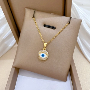 Detail of gold evil eye necklace with crystals displayed on jewelry box and silk