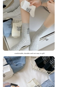 Close-up of minimalist cotton crew socks in various colors on white bedding