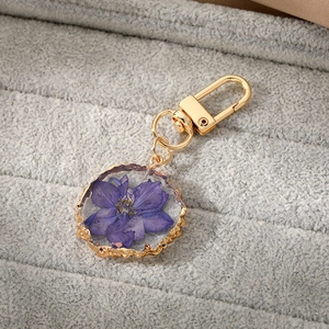 Detail of purple dried flower resin keychain with irregular gold metal plating edge