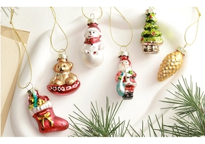 Close-up of assorted glass Christmas ornaments featuring snowmen and trees in a white tray