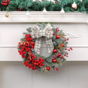 Christmas wreath with red berries, pine needles and checkered bow on a white fireplace