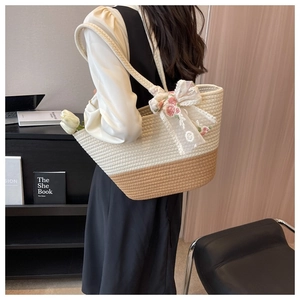 Detail of woven tote bag featuring a beige lace bow and pink flower embroidery