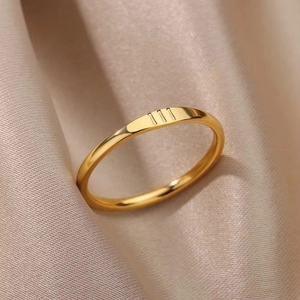 Detail of gold titanium steel ring with three vertical engraved lines on satin fabric