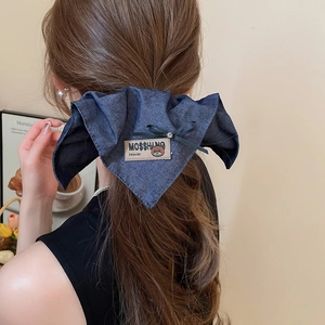 Detailed view of navy denim bow hair claw clip featuring beige bear patch embroidery