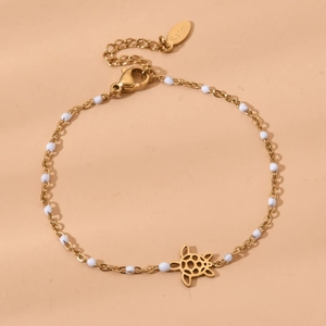 Detail of gold-plated turtle charm bracelet with white beads and S.Steel hallmark tag