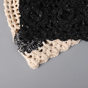 Close-up of handmade crochet fabric with black sequins and beige hollow grid pattern