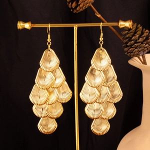 Macro view of gold tiered shell-shaped earrings hanging on a display stand