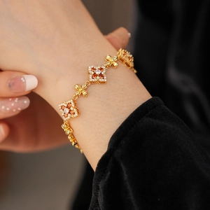 Primer plano de pulsera de flores vintage con circonitas naranjas y cadena de trébol