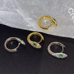 Detailed macro view of S925 silver snake earrings with white zircons and green gem eyes