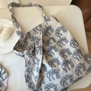 Detailed top view of a canvas tote bag featuring an all-over navy lamb embroidery pattern