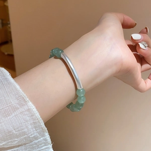 Detail view of green aventurine beaded bracelet with matte silver curved tube on wrist