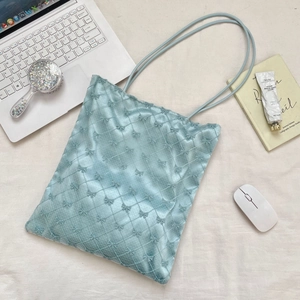 Détail d'un sac cabas en velours bleu clair avec matelassage à nœuds et décor