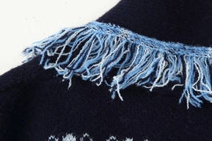 Detailed macro view of navy knit cardigan featuring light blue and white long tassel fringe