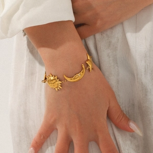 Detail of 18K gold plated stainless steel bracelet with sun, moon, and star charms on wrist