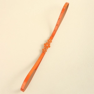 Detail of orange skinny belt with floral enamel buckle and adjustable holes for dresses
