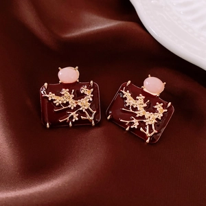 Detail view of vintage plum blossom earrings with red enamel and pink stones on silk