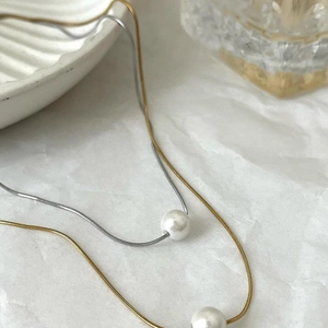 Double-layered gold and silver necklace featuring elegant white pearl pendants