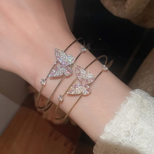 Close-up of golden butterfly open bracelets with pink and white crystal embellishments