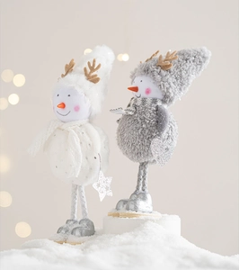 Close-up of plush Christmas snowman ornaments with knitted details and warm bokeh lights