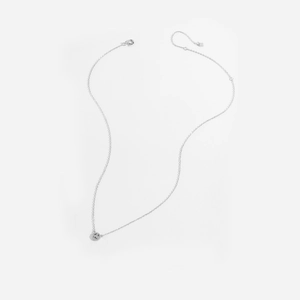 Detail of s925 silver necklace with textured round pendant on minimalist white background