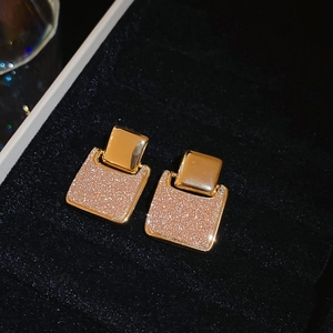 Detail of 18k gold plated square earrings with shimmering texture on black velvet