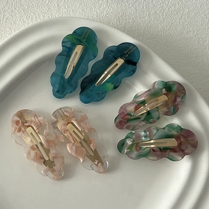 Détail des barrettes en acétate avec texture marbrée et design de nuage ondulé