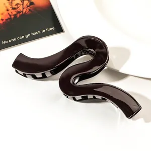 Close-up of a large wavy brown hair claw clip with a high-gloss finish on a white surface