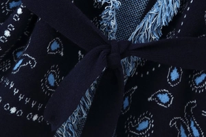 Macro shot of navy knit cardigan detailing textured jacquard pattern and tassel belt tie