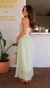 Détail d'une robe vert clair à fines bretelles avec ourlet à volants étagés et plis
