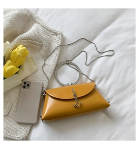 Detail of ginger yellow crossbody bag featuring a rhinestone-encrusted ring handle and silver chain