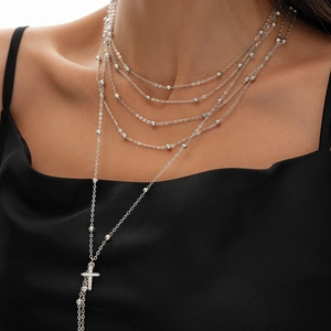Close-up of silver multilayer beaded chain with a zircon cross pendant on a black outfit