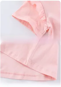 Détail d'une robe rose pour fille montrant les poignets à volants et l'ourlet