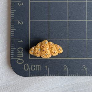 Macro view of a miniature resin croissant with colorful sprinkles on a scale mat