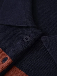 Detail of a knit striped polo sweater featuring a contrast collar and round four-hole button