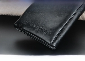Close-up of black leather wallet with lychee grain texture and embossed logo detailing