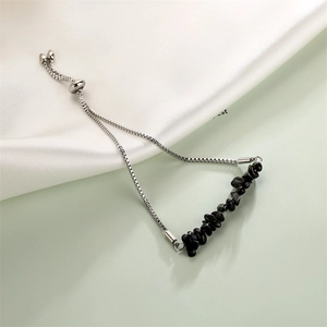 Detail of adjustable stainless steel bracelet with black stone beads on silk fabric