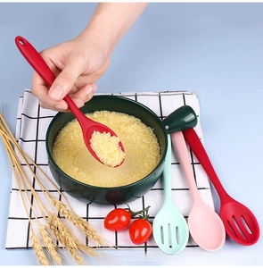 Silicone cooking spoon set in red and mint green used for serving soup from a green pot