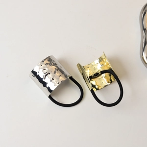 Detail of hammer textured gold and silver metal hair ties with black elastic bands
