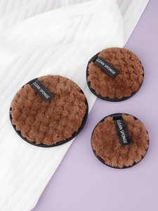 Detailed close-up of brown plush facial cleansing sponges with black ribbon handles