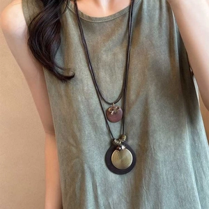 Détail d'un collier bohème double épaisseur avec pendentif en bois et spirale bronze