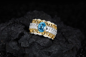Detailed view of wide vintage silver ring with blue topaz and white side stones on rock