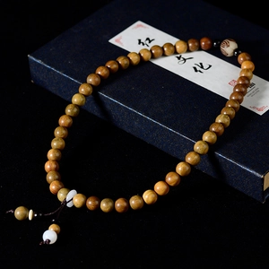 Macro detail of sandalwood beads bracelet with white jadeite accents in a blue gift box