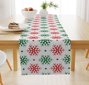 Detail of Christmas linen table runner featuring red and green snowflake patterns on wood
