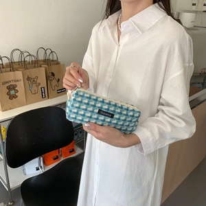 Trousse à carreaux bleus et blancs tenue à la main, texture en tissu tissé